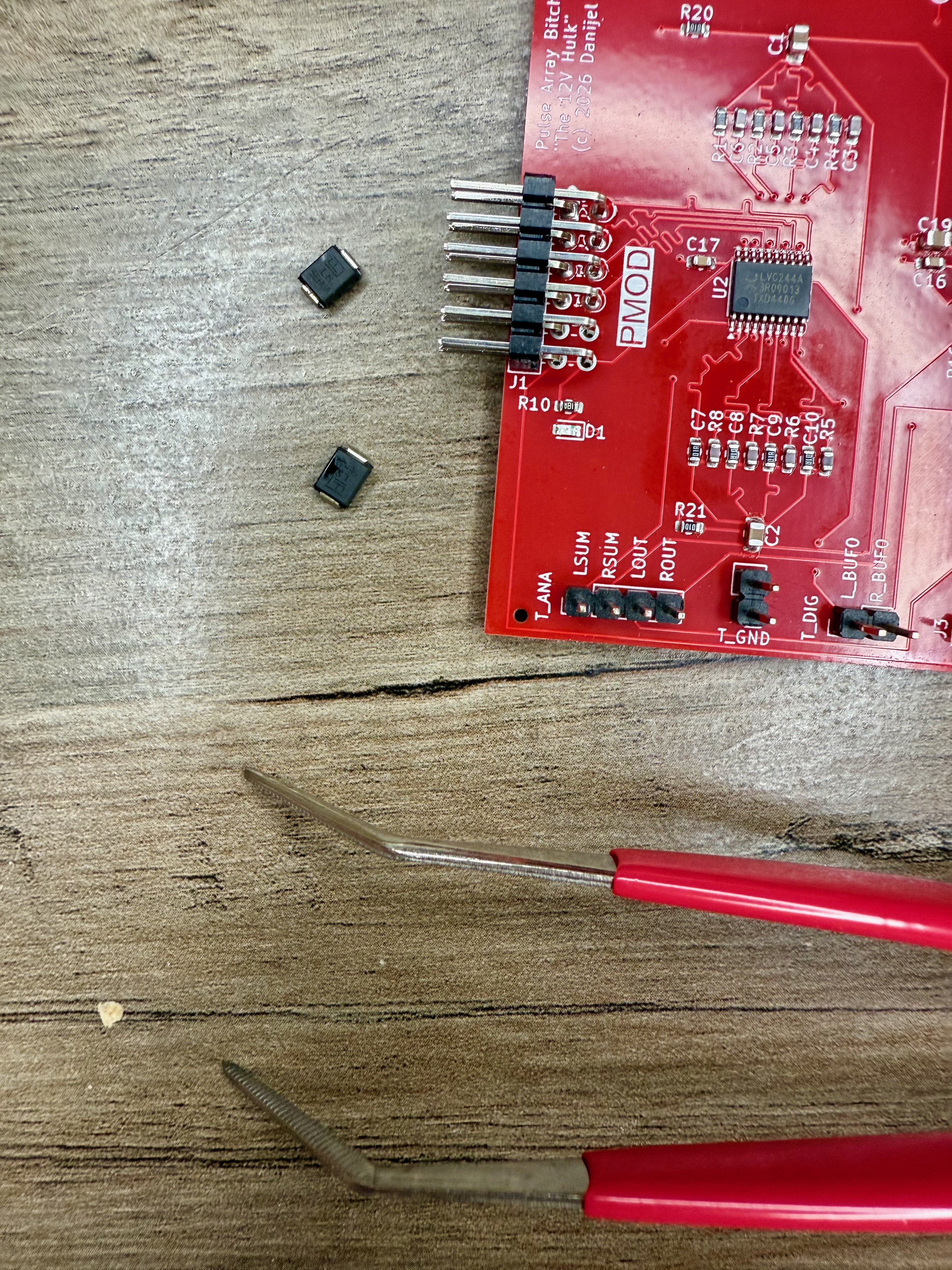 SMD rework on a red PCB with tweezers